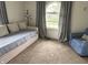 Relaxing bedroom features a comfortable daybed, accent chair, and large window with natural light at 5010 Melbourne Rd, Indianapolis, IN 46228
