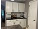 Kitchen counter featuring white cabinets, black countertop, and subway tile backsplash at 5010 Melbourne Rd, Indianapolis, IN 46228
