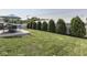 Landscaped backyard with green grass, trees, and a patio with an outdoor dining set at 5755 Victory Dr, Columbus, IN 47203