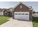 Brick home with a two-car garage, concrete driveway, and green grass yard in a suburban neighborhood at 5755 Victory Dr, Columbus, IN 47203