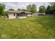 View of the backyard with a large green lawn, home, detached garage, and trees at 6408 Old Mill Dr, Indianapolis, IN 46221