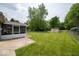 View of the backyard with a large green lawn, patio, home, shed, and trees at 6408 Old Mill Dr, Indianapolis, IN 46221