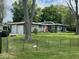 Charming single-story home featuring a well-manicured lawn, two-car garage, orange front door, and mature trees at , Indianapolis, IN 46227