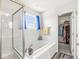 This bathroom features a bathtub with glass enclosure, a window, and a walk-in closet at , Greenwood, IN 46143