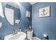 Stylish blue half bathroom with modern fixtures, a vanity and a decorative mirror at , Greenwood, IN 46143