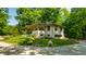 Home with covered porch and lovely lawn is surrounded by mature trees at 8717 Moore Rd, Indianapolis, IN 46278