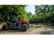 Close-up of a Polaris Ranger utility vehicle parked near the riverbank, surrounded by lush greenery on a sunny day at 8717 Moore Rd, Indianapolis, IN 46278