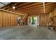 Open unfinished garage featuring wood framing, concrete flooring, and staircase, seamlessly transitioning to the outdoor scenery at 1021 N Alabama St, Indianapolis, IN 46202