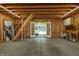 Unfinished garage revealing wood framing, concrete floor, and a staircase for storage with exterior access through double doors at 1021 N Alabama St, Indianapolis, IN 46202