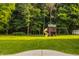 Expansive backyard featuring a playhouse set surrounded by lush green grass and mature trees at 10248 Noble Ct, Indianapolis, IN 46234