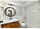 The bathroom features a tub and a wood vanity with round mirror and modern fixtures at 1053 Millwood Ct # 3, Indianapolis, IN 46260