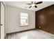 A bedroom featuring wood-look floors, a window, a ceiling fan, and a contrasting brown accent wall at 12157 Longstraw Dr, Indianapolis, IN 46236