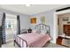 Bedroom with a wrought iron bed frame, white walls, chevron curtains, and access to an additional room at 140 W Hampton Dr, Indianapolis, IN 46208