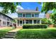 Beautiful home featuring a lush green lawn, vibrant landscaping, and a cozy enclosed front porch, located on a tree lined street at 140 W Hampton Dr, Indianapolis, IN 46208