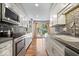 Modern kitchen featuring stainless steel appliances, wood floors, stone countertops, and access to backyard at 1408 126Th St, Carmel, IN 46033