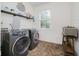 Functional laundry room with modern washer and dryer units, shelving, and window at 14662 Woodstone Cir, Fishers, IN 46037