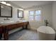 Luxurious bathroom with double sinks with a repurposed workbench vanity and a freestanding bathtub at 1512 Bellefontaine St, Indianapolis, IN 46202