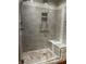 Modern bathroom shower features stone tiling, a glass door, built in seat, and a convenient storage niche at 16956 Fulton Pl, Westfield, IN 46074