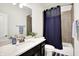 A well-lit bathroom with a white countertop, dark vanity and blue shower curtain at 17319 Henslow Dr, Westfield, IN 46074