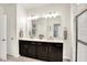 Bright bathroom features double vanity with dark cabinets and a large mirror illuminated by contemporary vanity lighting at 17319 Henslow Dr, Westfield, IN 46074