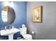 Chic powder room featuring blue walls, a round mirror, and pedestal sink with modern fixtures at 17319 Henslow Dr, Westfield, IN 46074