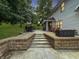 Multi-level patio with outdoor dining and lounge seating, stone steps and lush landscaping at 2015 Deer Lake Dr, Martinsville, IN 46151