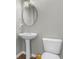 Well-lit half-bathroom with a pedestal sink, toilet, and oval mirror providing a simple and clean design at 258 Coatsville Dr, Westfield, IN 46074