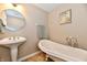Charming bathroom boasts a claw foot tub, pedestal sink, and elegant round mirror, creating a classic aesthetic at 2805 Rylee Ct, Greenwood, IN 46143
