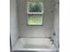 Renovated bathroom featuring new tub, marble tile surround and updated window at 330 S Butler Ave, Indianapolis, IN 46219