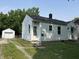 Quaint single-story home with white siding, black roof, and a detached single-car garage at 330 S Butler Ave, Indianapolis, IN 46219
