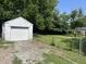 View of a detached one-car garage with a white door and siding, surrounded by a chain link fence at 330 S Butler Ave, Indianapolis, IN 46219