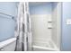 This bathroom features a shower with a white shower curtain, white tile, and light blue walls at 3414 Ferncliff Ave, Indianapolis, IN 46227