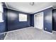 This bedroom features blue walls, neutral carpet, white trim, a window, and a closet at 3414 Ferncliff Ave, Indianapolis, IN 46227