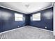 This bedroom features blue walls, neutral carpet, white trim, and natural light from two windows at 3414 Ferncliff Ave, Indianapolis, IN 46227