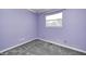 This bedroom features purple walls, neutral carpet, and a window that lets in natural light at 3414 Ferncliff Ave, Indianapolis, IN 46227