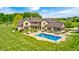 Beautiful aerial view of the brick home highlighting the pool, outdoor living spaces, and pristine landscaping at 4181 Whitetail Woods Dr, Bargersville, IN 46106