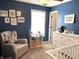 Bedroom features blue walls, a window, rocker, and a white dresser with a crib at 5702 Deer Valley Ct, Columbus, IN 47201