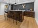 Basement bar with wooden bar and stools, white countertops, wood cabinets, and decorative wallpaper at 5946 Stafford Way, Indianapolis, IN 46228