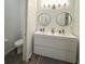 This is a bathroom with dual vanity, two round mirrors, horizontal shiplap, and wood-look floor at 5946 Stafford Way, Indianapolis, IN 46228