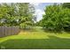 Well-maintained backyard with lush green lawn, privacy fence, and mature trees at 5966 Draycott Dr, Indianapolis, IN 46236