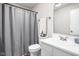 Well-lit bathroom featuring a white vanity, toilet, and a shower with a gray curtain at 5966 Draycott Dr, Indianapolis, IN 46236