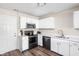 Modern kitchen with white cabinets, black appliances, and quartz countertops at 5966 Draycott Dr, Indianapolis, IN 46236