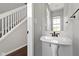 Hall bathroom with a pedestal sink, mirror, and a view of the staircase at 603 Daviess Dr, Westfield, IN 46074