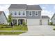 Two-story home featuring a three-car garage, well-manicured lawn, and a charming front porch at 6305 N Woodhaven Dr, McCordsville, IN 46055