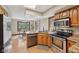 Kitchen featuring stainless steel appliances, wood cabinetry, granite counters, and an adjacent dining area at 6983 White Oak Dr, Avon, IN 46123