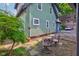 Landscaped backyard featuring a lush green tree, outdoor seating, and partial view of the home's exterior at 715 Kessler Blvd E Dr, Indianapolis, IN 46220