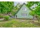 Unique green home with a distinct architectural design and luscious lawn framed by lush greenery at 715 Kessler Blvd E Dr, Indianapolis, IN 46220
