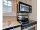 View of the kitchen cooktop and microwave, enhanced by a bright window and tile backsplash at 715 Kessler Blvd E Dr, Indianapolis, IN 46220