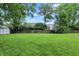 Large, well-maintained backyard featuring lush green grass, a wood fence, mature trees, and a storage shed at 7430 Railway Ct, Indianapolis, IN 46256