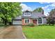 Charming front exterior featuring a brick facade and inviting red door, with mature trees and a lush lawn at 7430 Railway Ct, Indianapolis, IN 46256